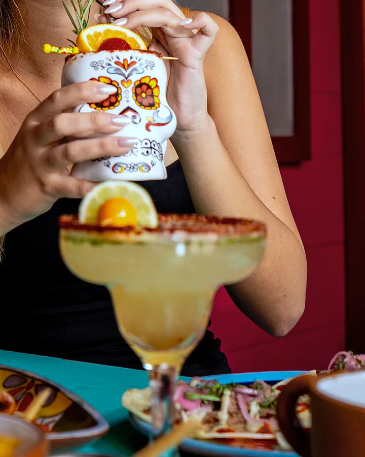 Margarita escarchada con chile y un vaso de calavera de talavera en la mesa