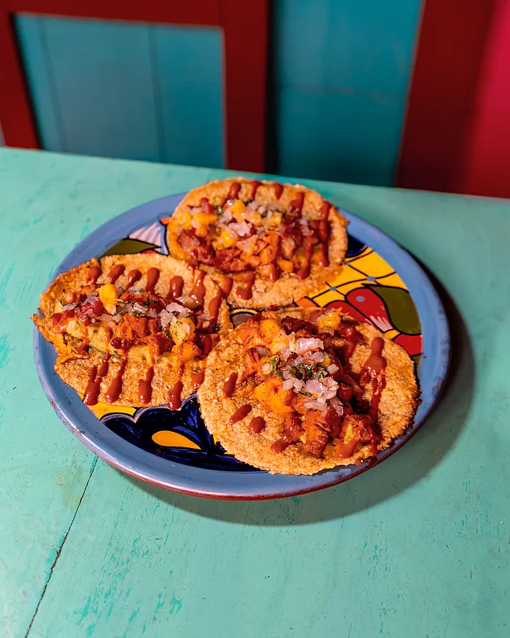 Tacos al pastor con piña, crema y cebolla encurtida en plato de talavera