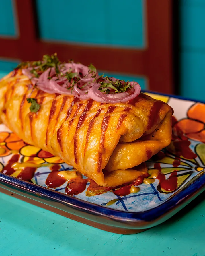 Burrito norteño con salsa taquera y cebolla encurtida en plato de talavera