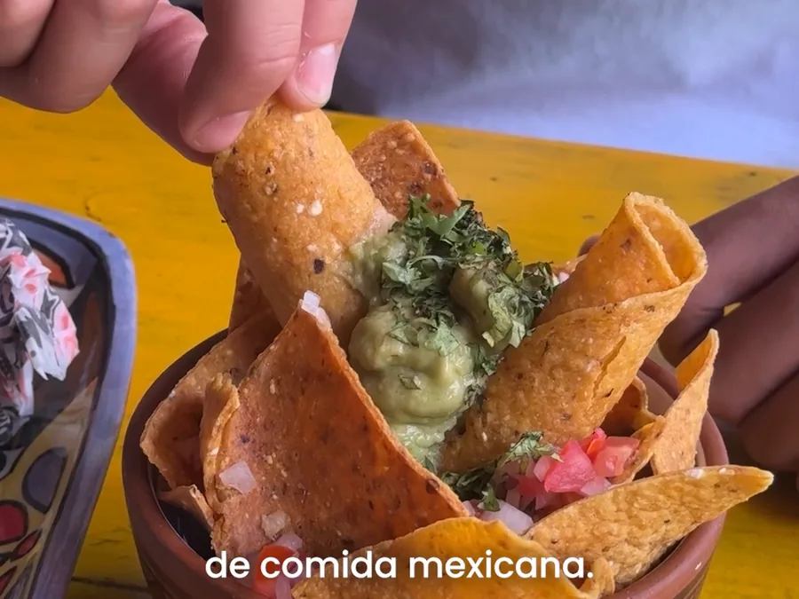 Mano tomando un nacho con guacamole del nacho cup