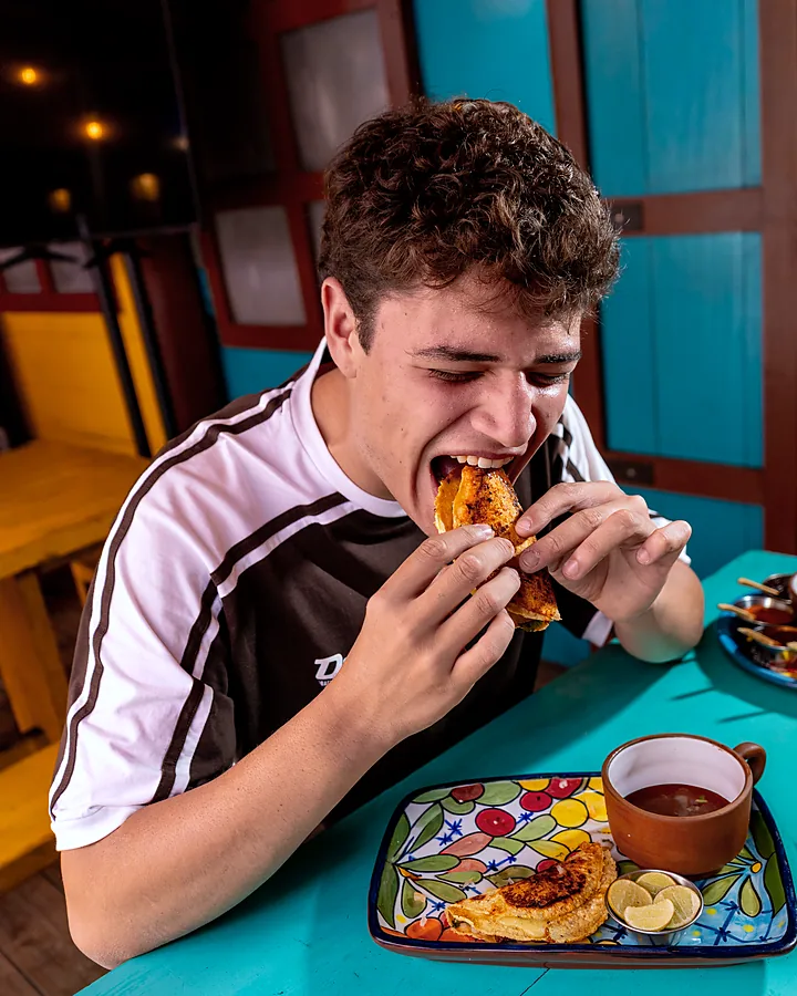 Cliente dándole una mordida a un taco en la mesa