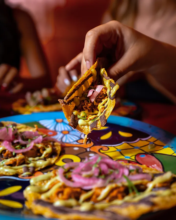 Mano levantando un taco de un plato de talavera