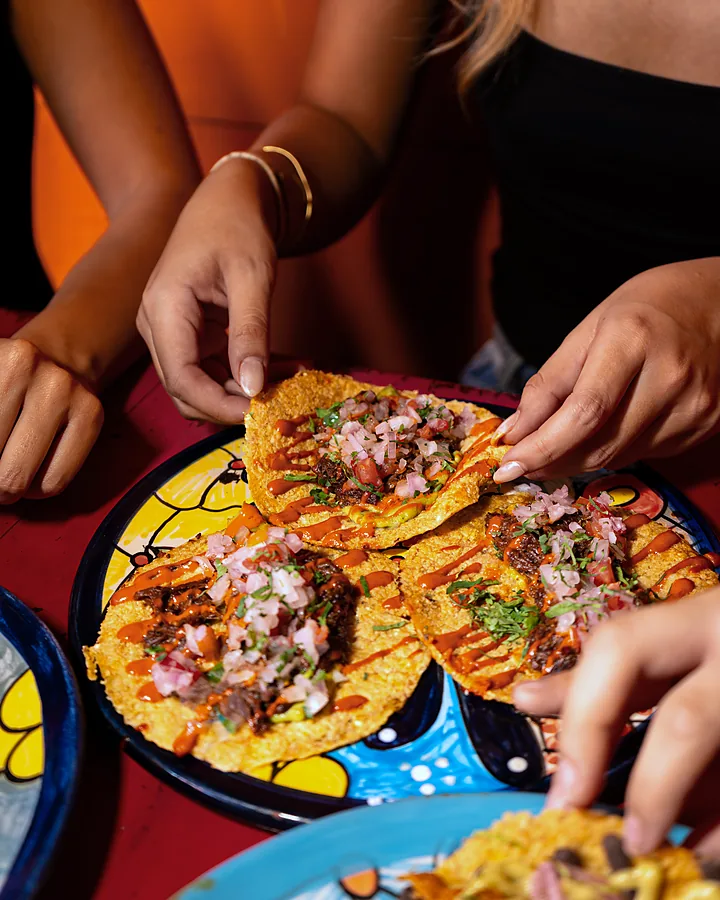 Manos tomando tostadas de un plato compartido