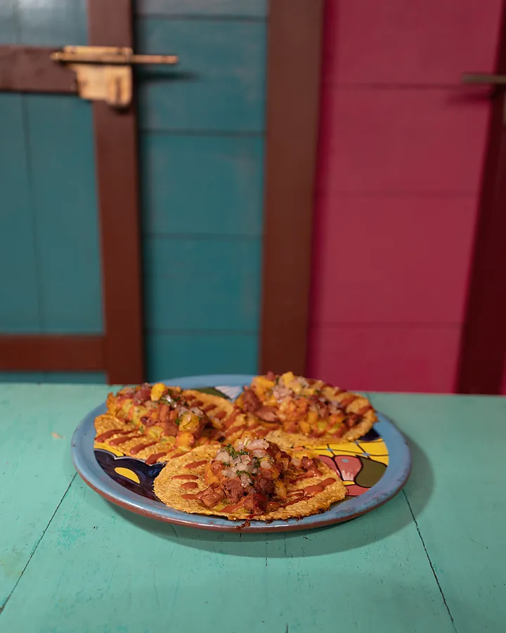 Plato de tostadas sobre la mesa turquesa, con las paredes rosas del local
