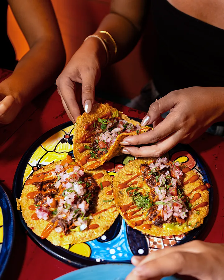 Amigos compartiendo tacos de un mismo plato