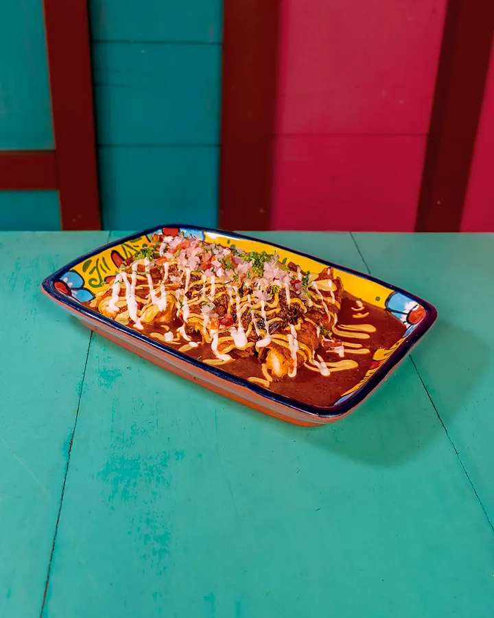 Plato con crema y salsa roja sobre una mesa turquesa del local